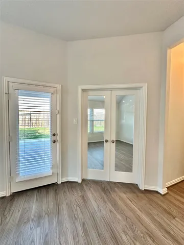 an empty room with wooden floor closet and windows