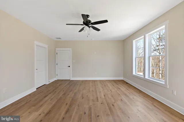 a view of empty room with wooden floor and fan