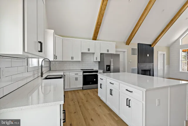 a kitchen with stainless steel appliances white cabinets a sink a stove a refrigerator and white cabinets