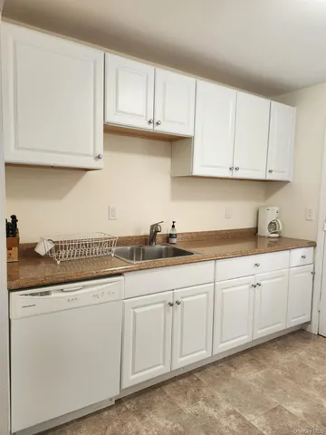 a kitchen with granite countertop white cabinets and a sink