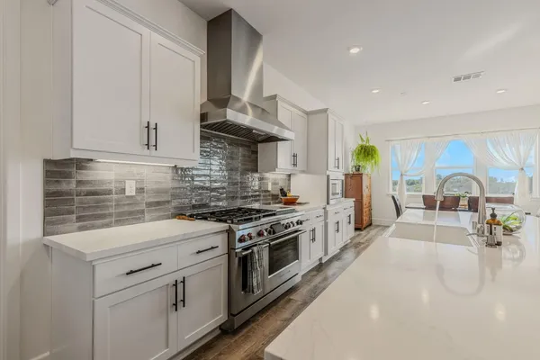 a kitchen with stainless steel appliances granite countertop a stove a sink and a white cabinets