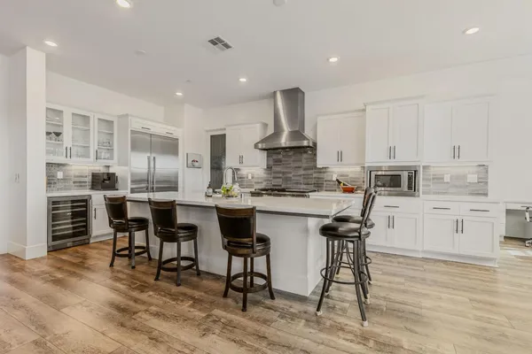 a kitchen with stainless steel appliances kitchen island granite countertop a table chairs sink and cabinets
