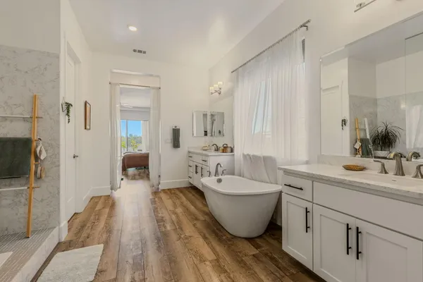 a spacious bathroom with a double vanity sink a mirror and a bathtub