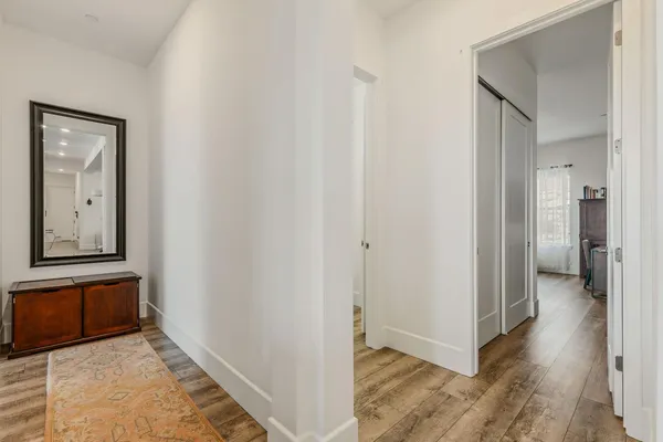 a view of a hallway with wooden floor and closet