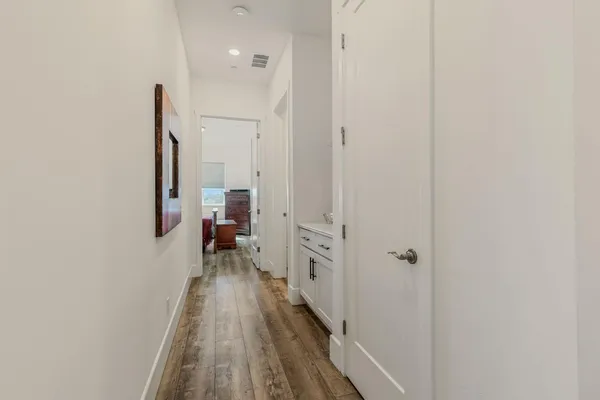 a view of a hallway with wooden floor and a bathroom