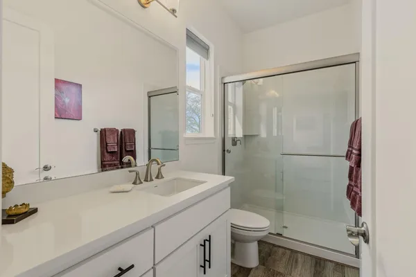 a bathroom with a shower sink vanity mirror and toilet