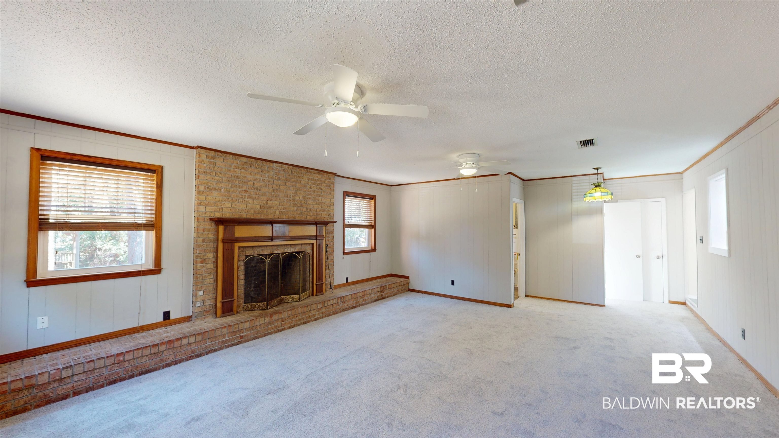 1471 Cedar Crescent Drive Mobile, AL 36605 - Photo 13 of 28 Unfurnished living room featuring carpet floors, a ceiling fan, a brick fireplace, ornamental molding, and a textured ceiling