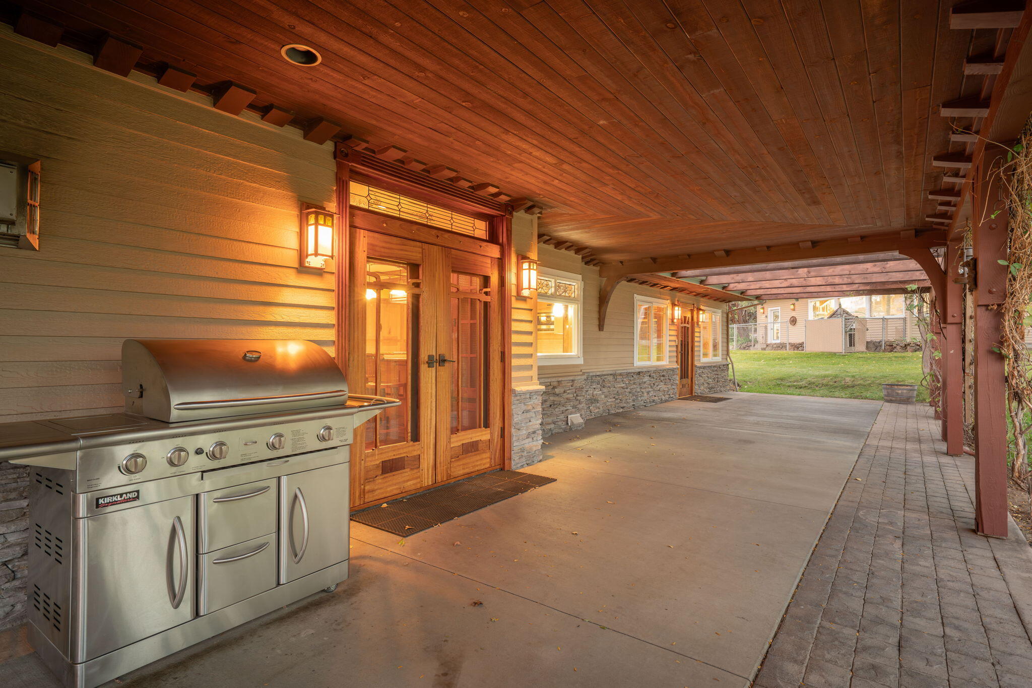 21925 Bear Creek Road Bend, OR 97702 - Photo 33 of 104 Side entryway double-doors are Brazilian cherry w/African mahogany screen doors in the Green & Green style. Handmade stained glass and copper lighting at night. Large concrete covered porch w/gas grill