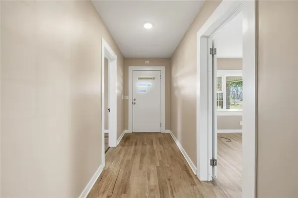 a view of a hallway with wooden floor and a bathroom