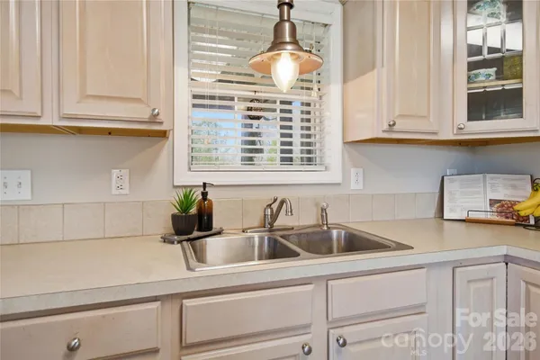 a kitchen with white cabinets stainless steel appliances and window