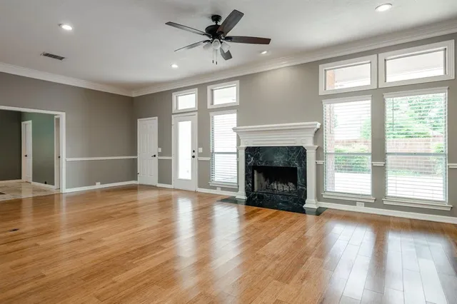 a view of an empty room with wooden floor fireplace and a window