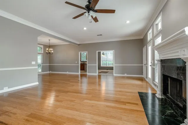 an empty room with wooden floor fireplace and windows