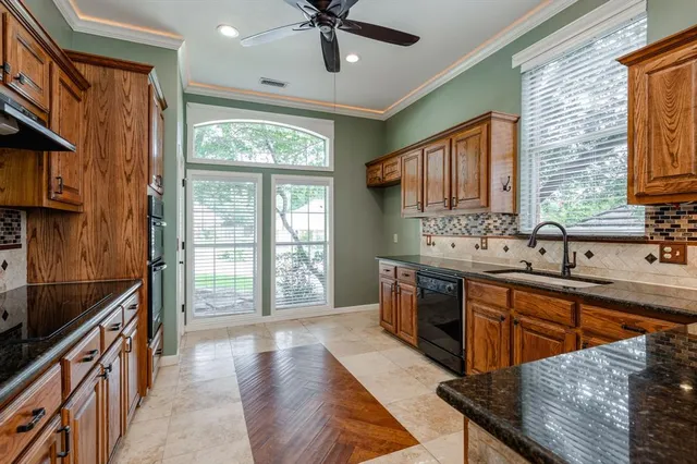 a large kitchen with stainless steel appliances granite countertop a refrigerator a sink dishwasher a stove and a dining table with wooden floor