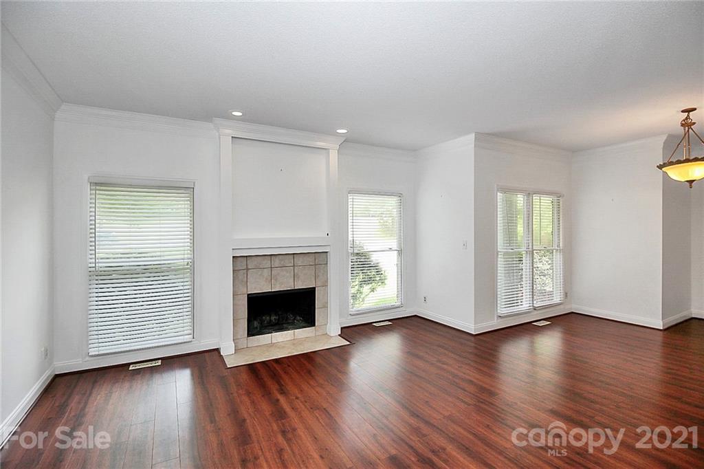 4900 Spring Lane Charlotte, NC 28213 - Photo 6 of 31 an empty room with wooden floor fireplace and windows