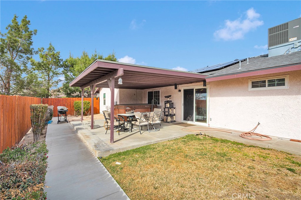 14190 Tehachapi Road Apple Valley, CA 92307 - Photo 33 of 39 a view of a patio with table and chairs under an umbrella with wooden fence