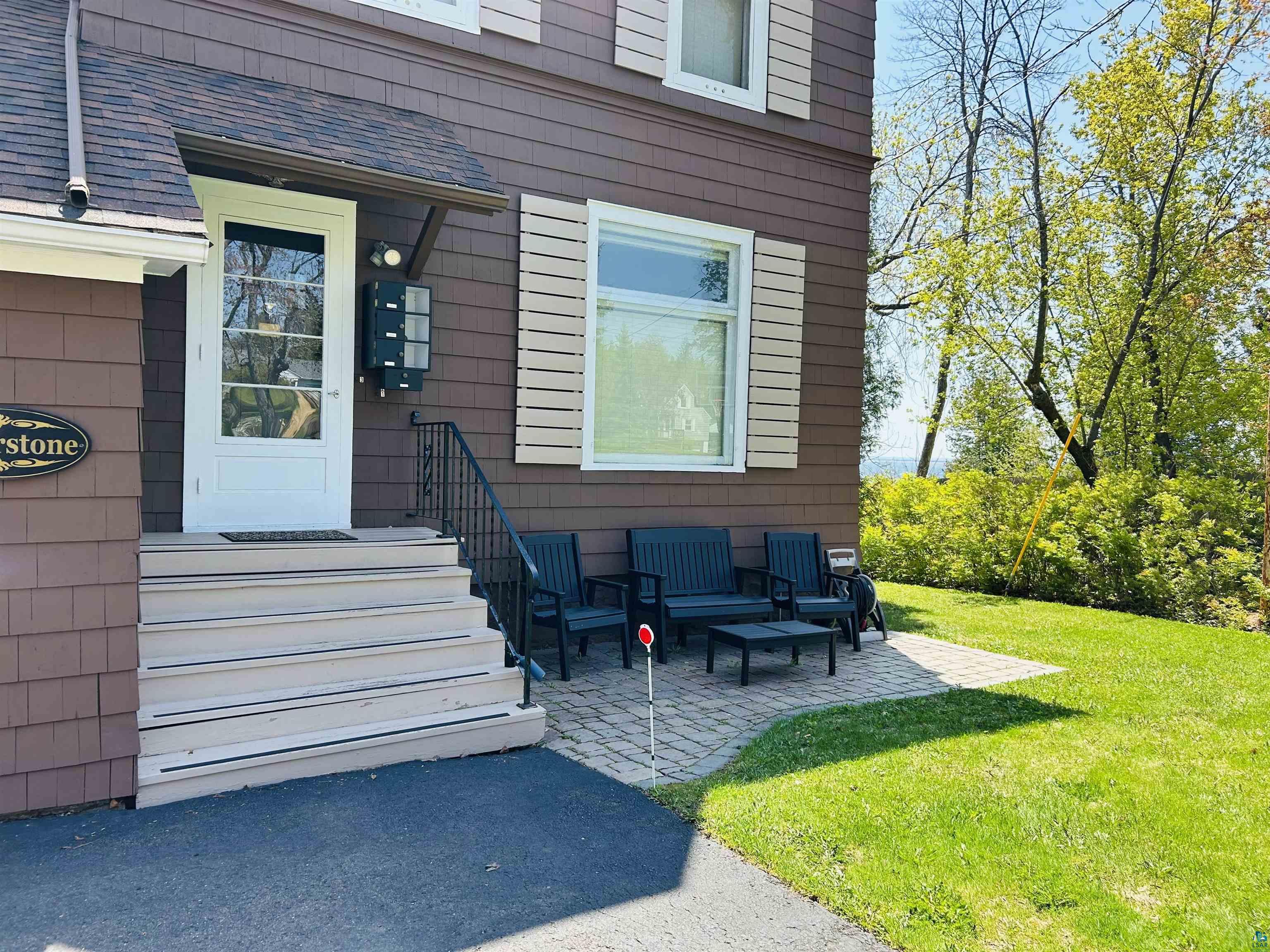 5090 London Road, Unit 1 Duluth, MN 55804 - Photo 5 of 54 Property exterior featuring brown shingle siding, a white front entry door with glass panels, and a covered porch