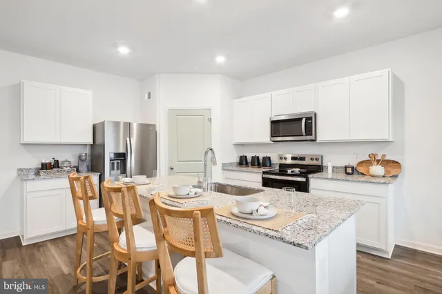 a kitchen with stainless steel appliances granite countertop a stove top oven a sink dishwasher a dining table and chairs with wooden floor