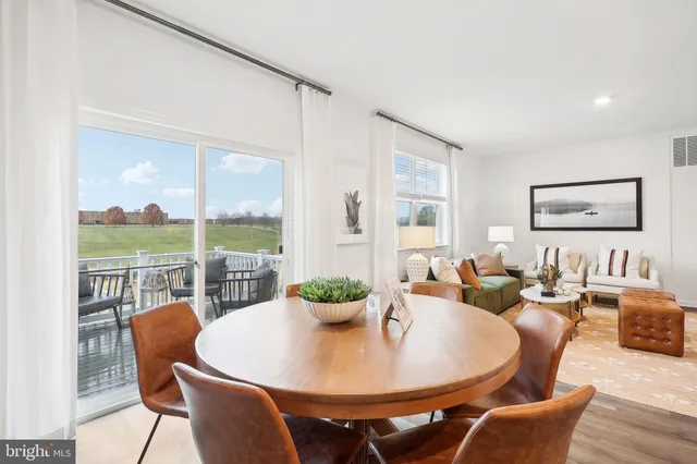 a kitchen with stainless steel appliances granite countertop a refrigerator a stove a dining table and chairs with wooden floor