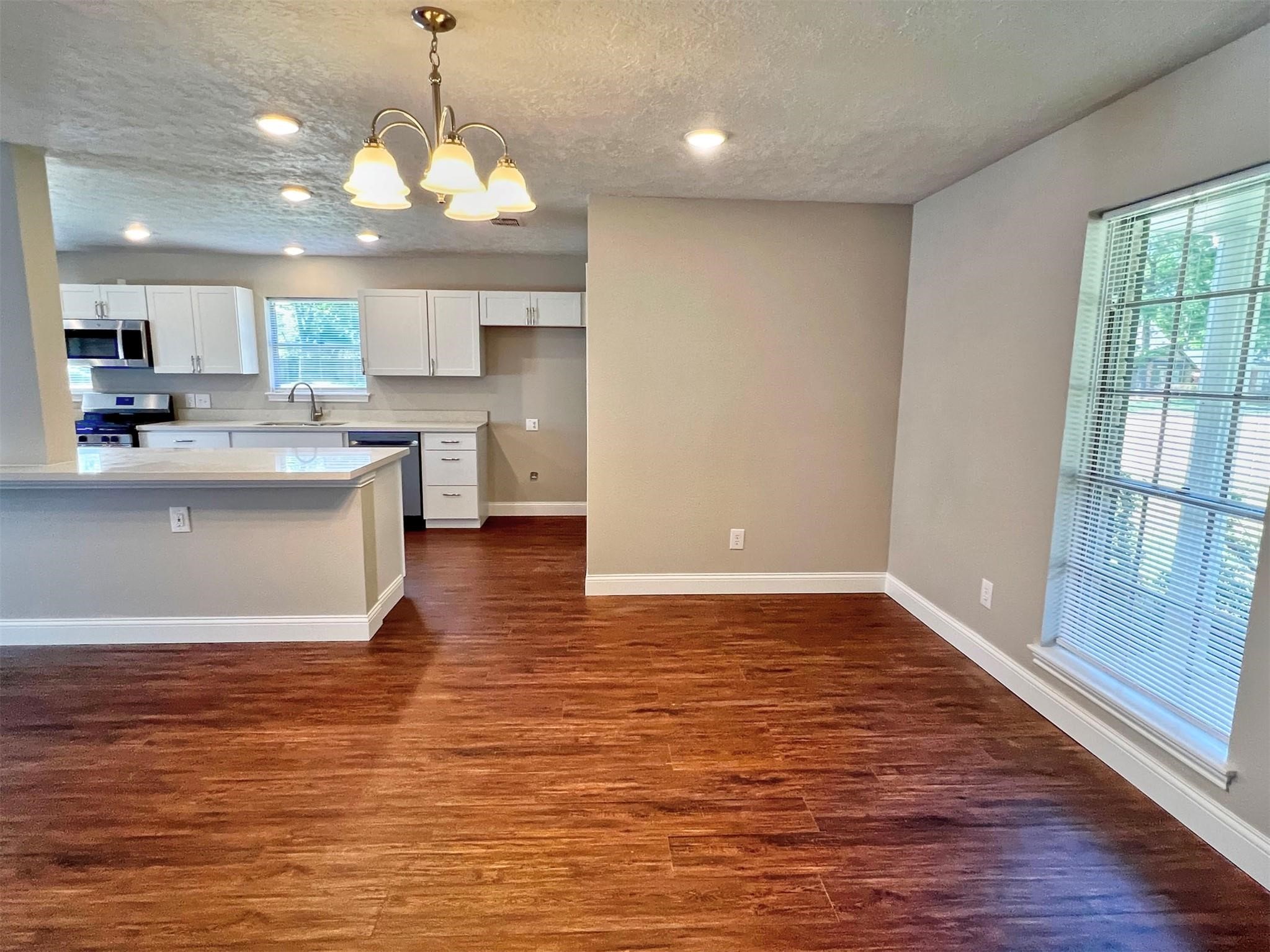 415 Sevenhampton Lane Houston, TX 77015 - Photo 11 of 32 a view of a kitchen with kitchen island a stove a wooden floor and a large window