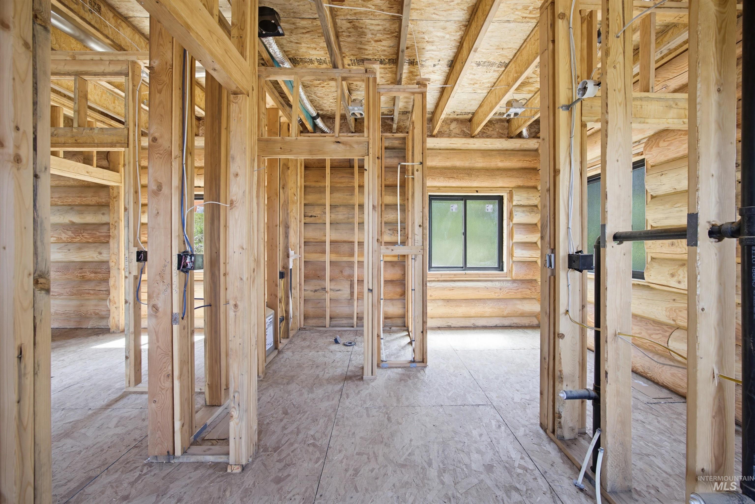 3322 Big Creek Road New Meadows, ID 83654 - Photo 37 of 50 New construction framing with exposed wooden studs, oriented strand board subflooring, black-framed windows, and visible electrical and plumbing rough-ins