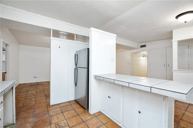 a view of a refrigerator in kitchen and white cabinets