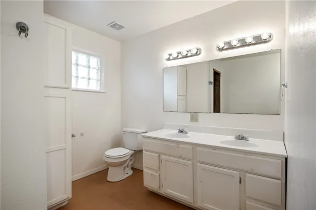 a spacious bathroom with a toilet a sink and a mirror