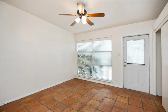 an empty room with windows and fan