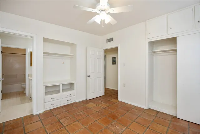 a view of an empty room with cabinet and a ceiling fan