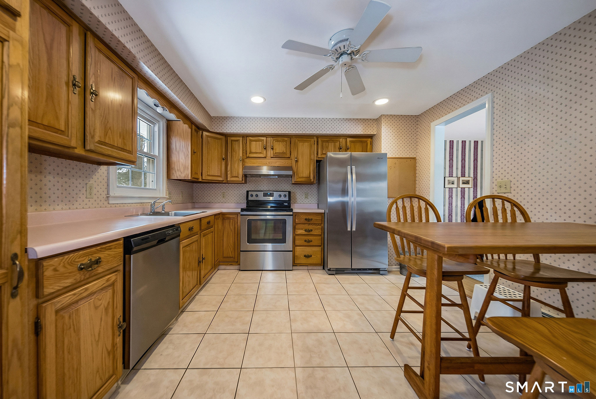 162 Yankee Peddler Path Madison, CT 06443 - Photo 9 of 39 a kitchen with stainless steel appliances granite countertop a stove a sink dishwasher a dining table and chairs with wooden cabinets