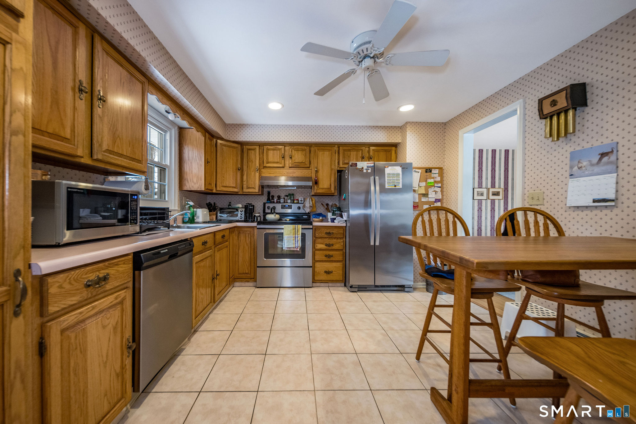 162 Yankee Peddler Path Madison, CT 06443 - Photo 10 of 39 a kitchen with stainless steel appliances granite countertop a stove a sink dishwasher and a refrigerator with wooden cabinets
