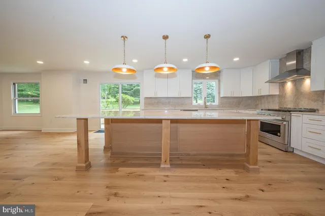 a kitchen with kitchen island granite countertop wooden floors white cabinets and stainless steel appliances