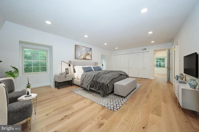 a spacious bedroom with a bed a couch and a flat screen television