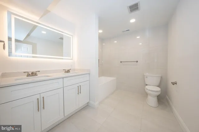a bathroom with a granite countertop sink a toilet and a large mirror