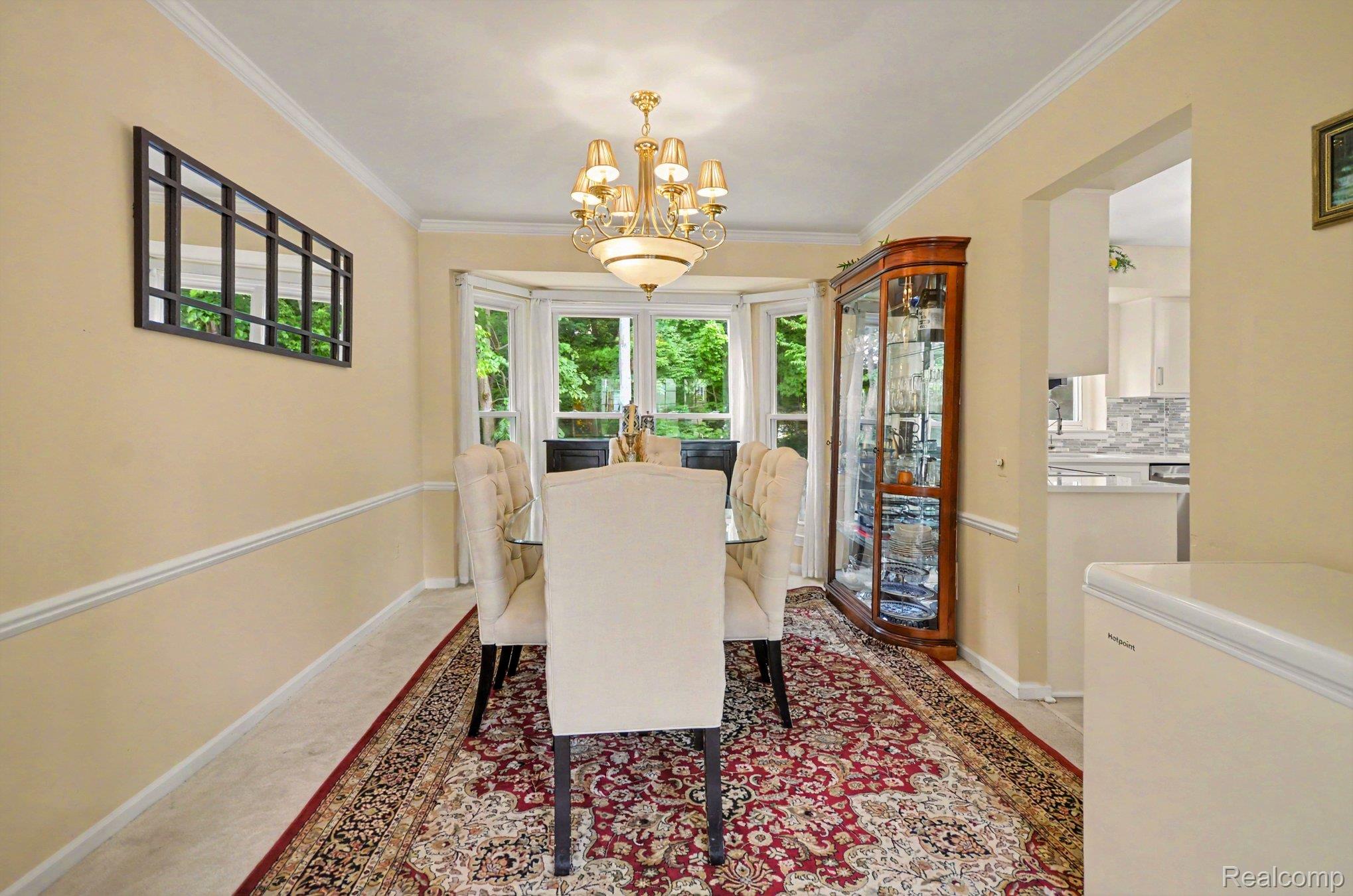 425 Thornridge Court Rochester, MI 48307 - Photo 14 of 35 Bay window dining area with crown molding, chair rail molding, and a chandelier