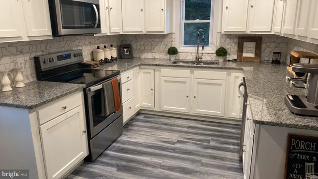 a kitchen with granite countertop a sink stove and cabinets