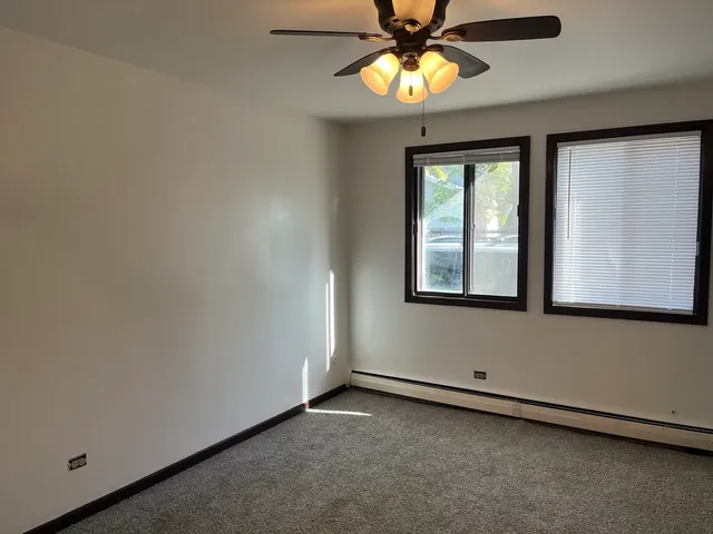 an empty room with a window and a chandelier fan