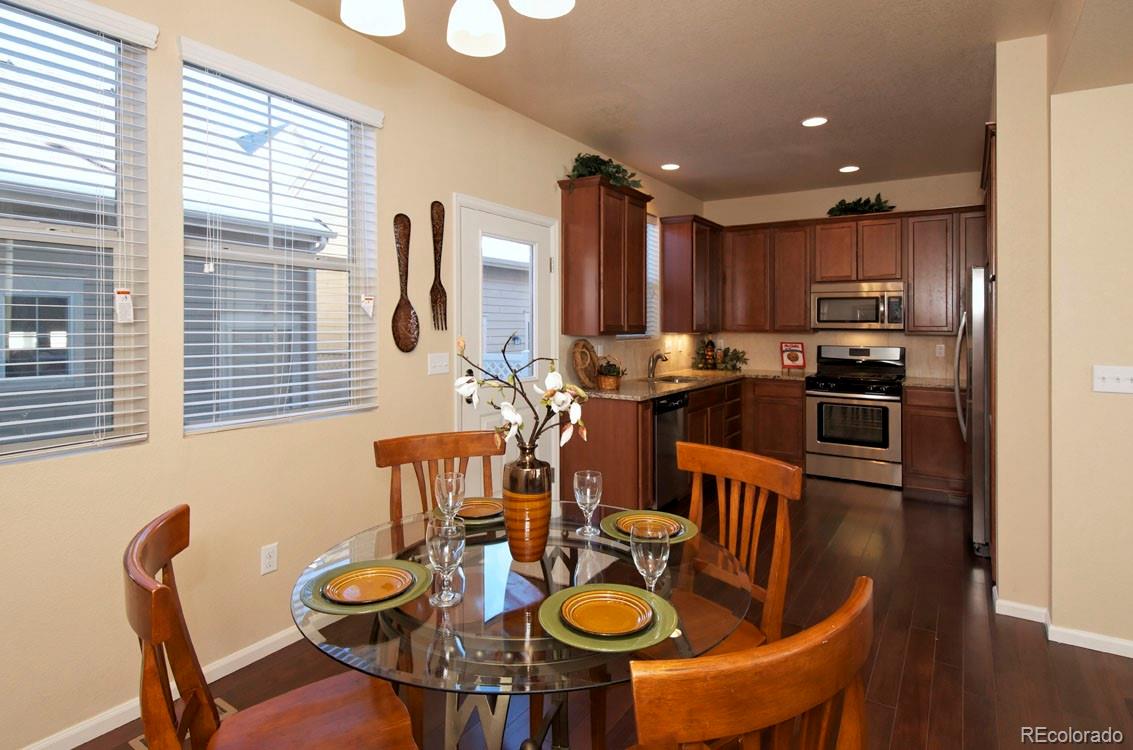 10296 Bellwether Lane Lone Tree, CO 80124 - Photo 7 of 29 a kitchen with stainless steel appliances granite countertop a stove a refrigerator a kitchen island a table and chairs