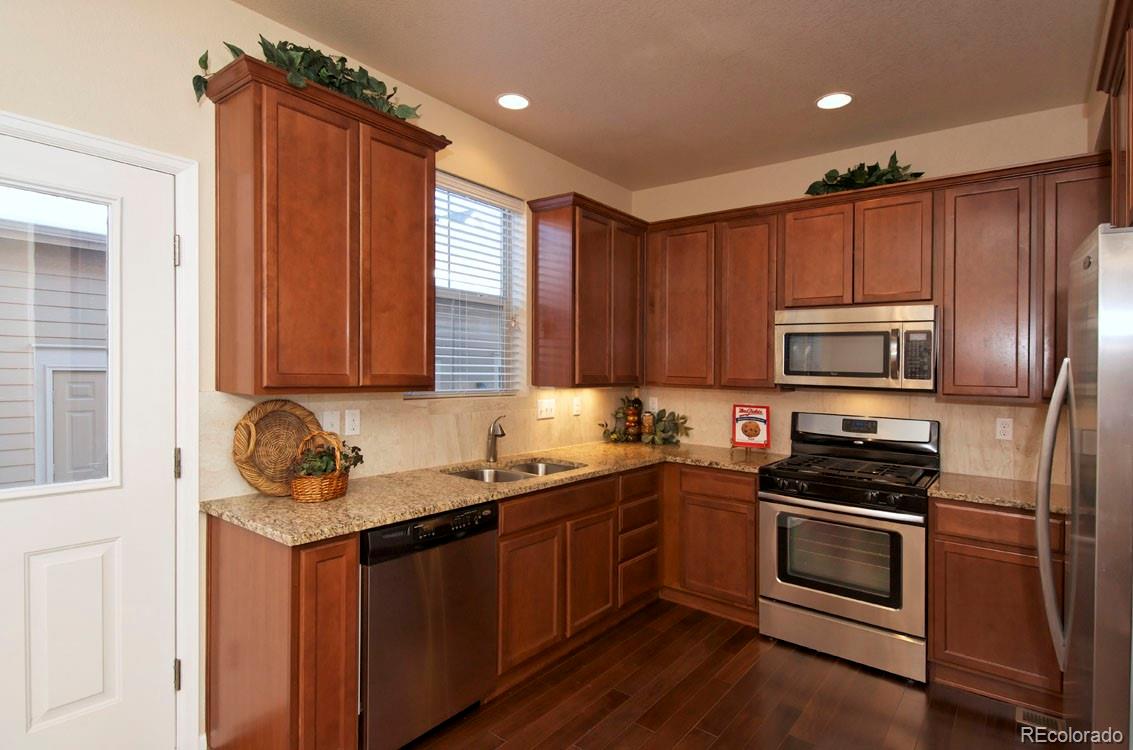 10296 Bellwether Lane Lone Tree, CO 80124 - Photo 10 of 29 a kitchen with granite countertop a sink cabinets and stainless steel appliances