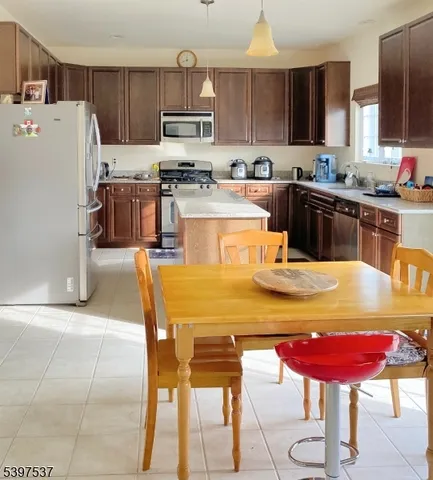 a kitchen with stainless steel appliances kitchen island granite countertop a table chairs sink and cabinets