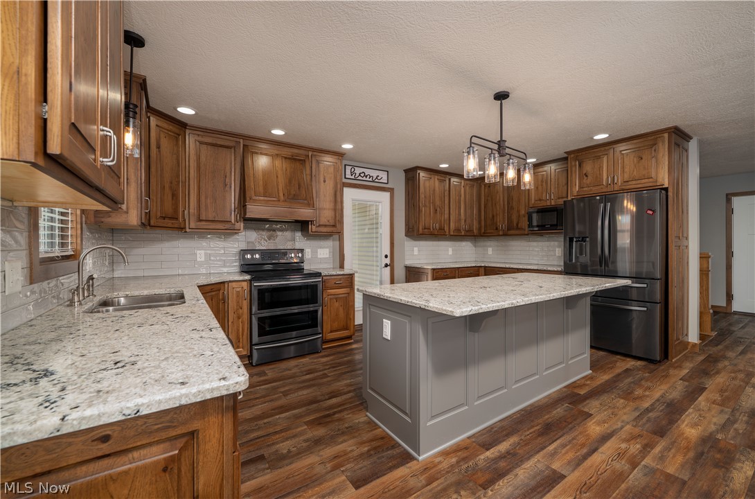 3515 Eastport Road Southeast Dennison, OH 44621 - Photo 7 of 41 Kitchen featuring wood cabinetry, white subway tile backsplash, light-toned countertops, a center island with paneling, and wood-finish flooring