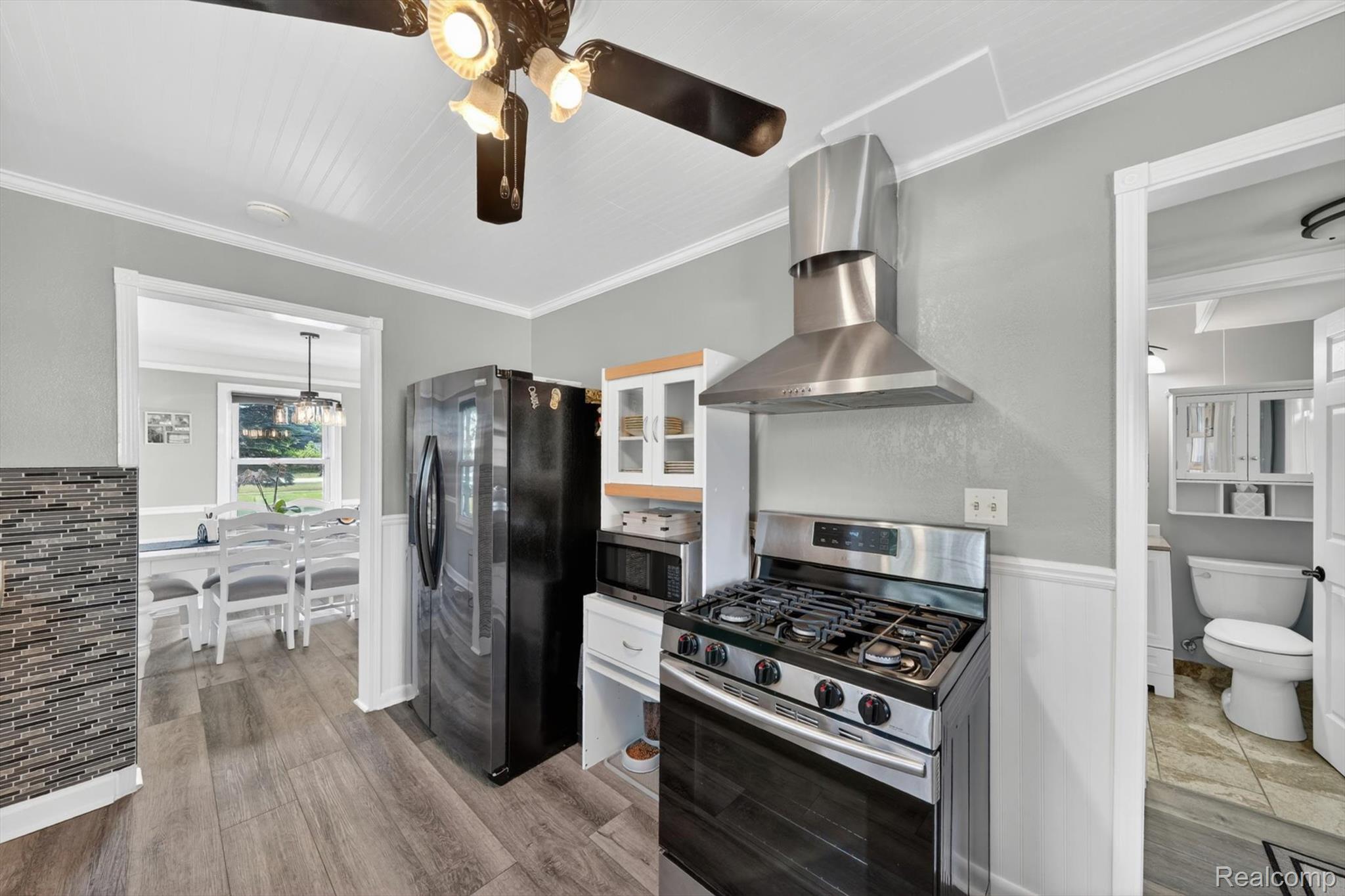 2861 John R Road Rochester, MI 48307 - Photo 12 of 54 Kitchen featuring a gas range with stainless steel hood, adjacent refrigerator, wood-finish flooring, and white wainscoting