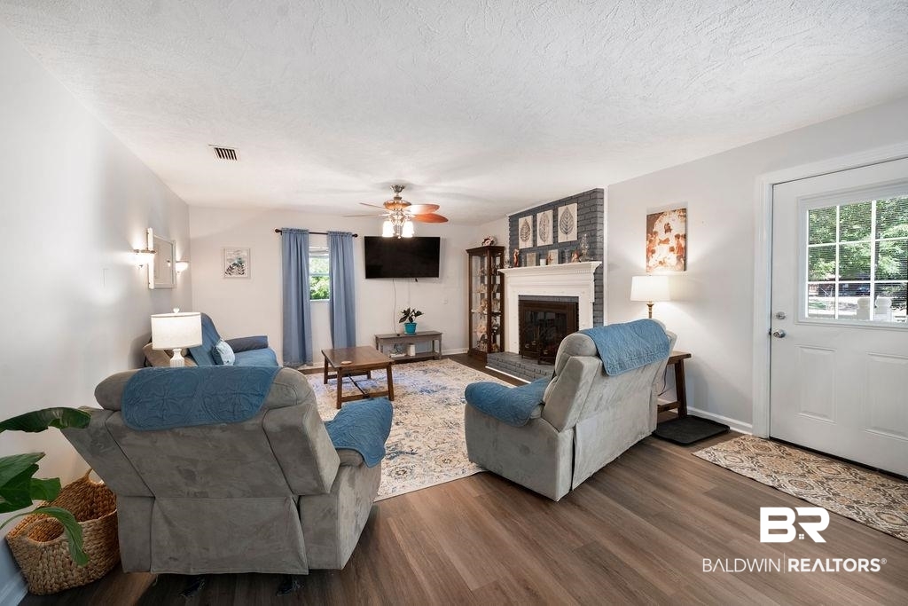 11901 Old Moffat Road Wilmer, AL 36587 - Photo 2 of 39 Living area with wood finished floors, a fireplace, a textured ceiling, and ceiling fan