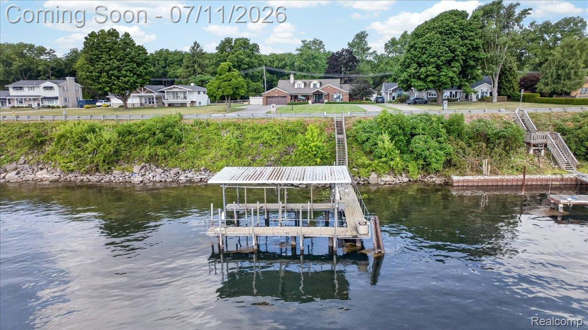 23750 East River Road Grosse Ile, MI 48138 - Photo 51 of 54 Waterfront property featuring a covered boat dock with a metal roof, a wooden pier, and two sets of wooden stairs providing water access
