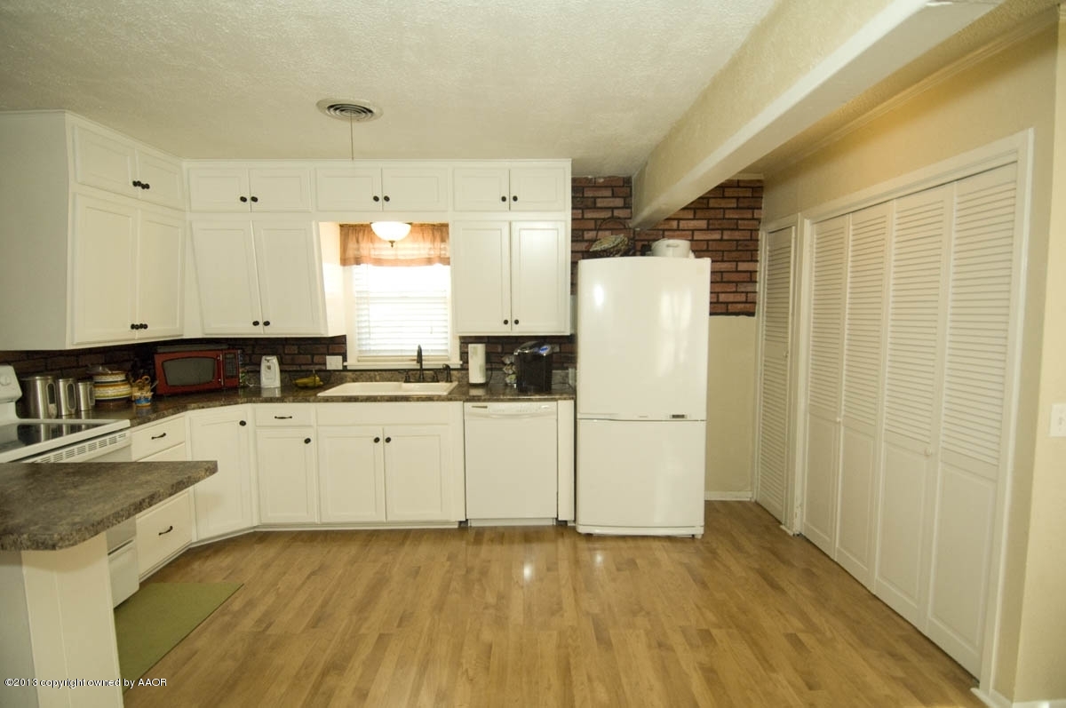 4227 South Jackson Street Amarillo, TX 79110 - Photo 9 of 23 a kitchen with a refrigerator a sink and white cabinets