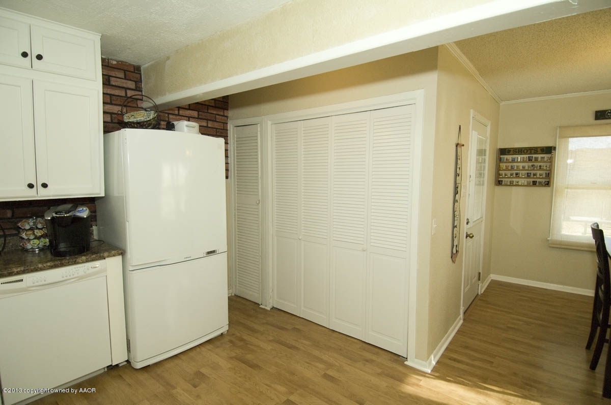 4227 South Jackson Street Amarillo, TX 79110 - Photo 10 of 23 a view of a refrigerator in kitchen and an empty room with wooden floor