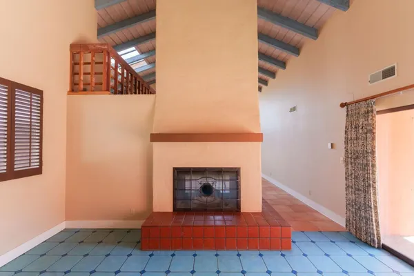 an empty room with wooden floor fireplace and windows