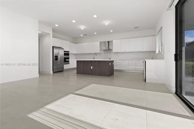 a large white kitchen with kitchen island a sink a stove and a refrigerator