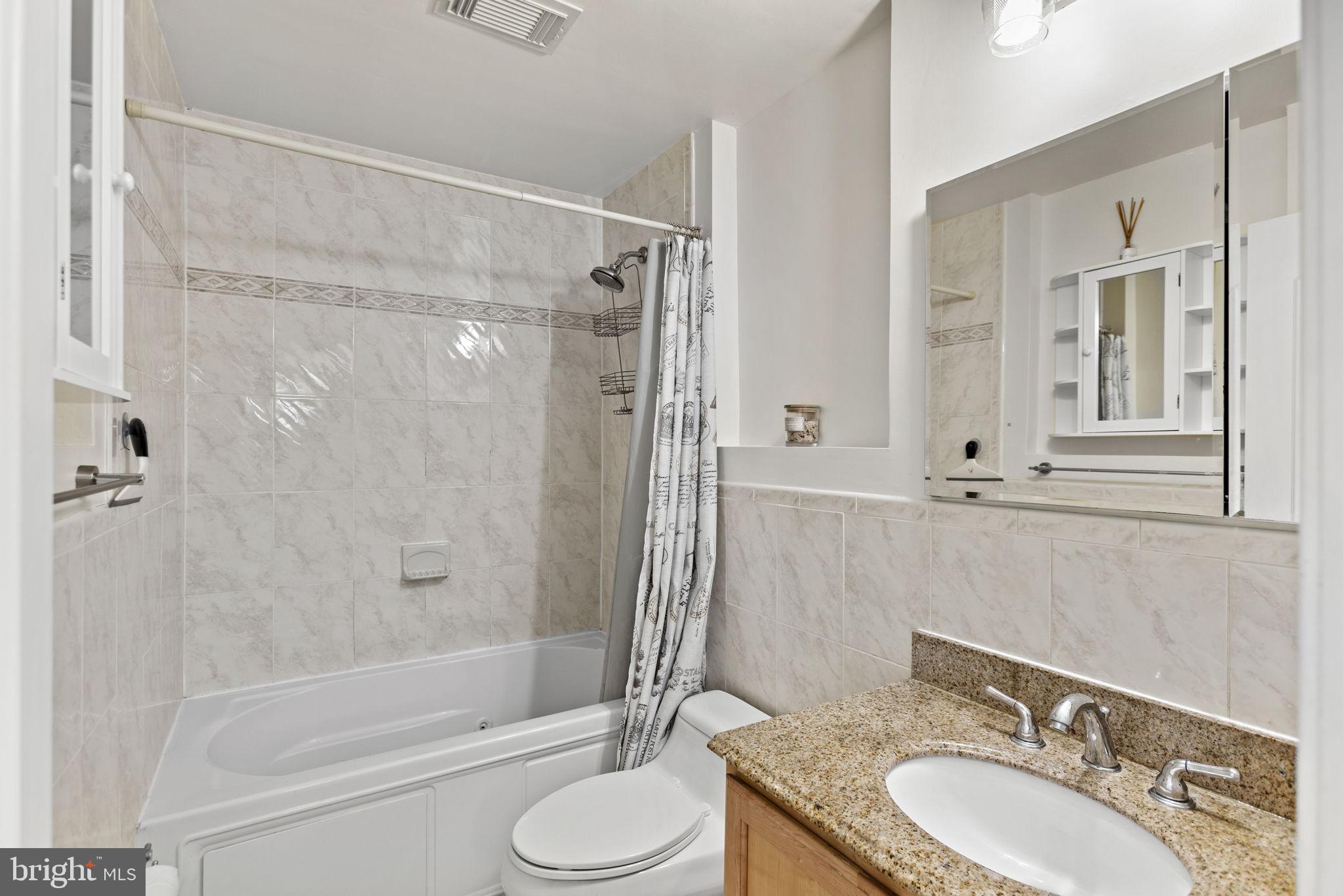 1437 Spring Road Northwest, Unit 21 Washington, DC 20010 - Photo 20 of 25 a bathroom with a granite countertop sink toilet and shower
