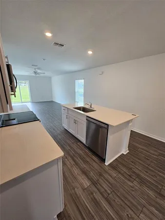 a large kitchen with stainless steel appliances a large counter top a stove and a wooden floors