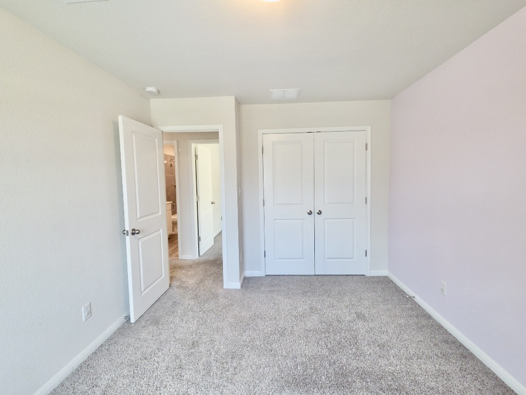 110 Grapefruit Road Hutto, TX 78634 - Photo 20 of 28 Carpeted room featuring a double-door closet, a single paneled door, and neutral-toned walls